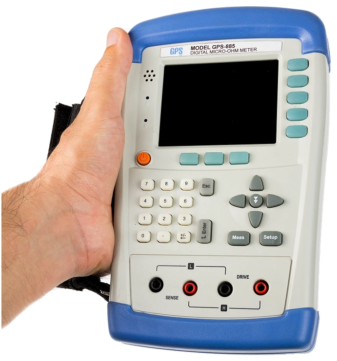 The GPS LTD GPS-885 micro-ohm meter held in one hand, showing its size relative to a hand and the wrist strap fitted to the left side